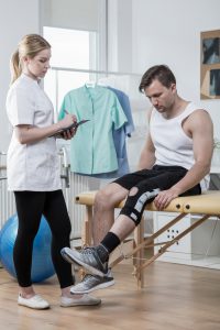 Man after knee ligament injury in physiotherapist's office